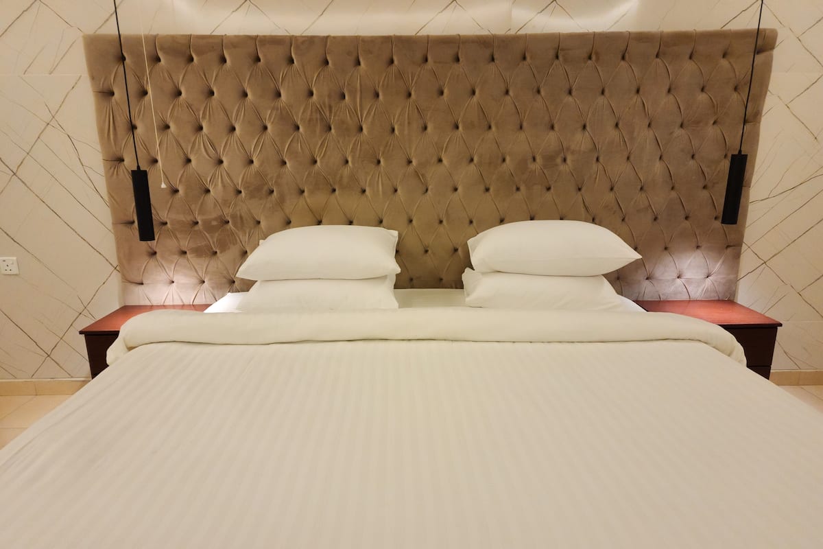 A bed with a tufted headboard, two bedside tables, and a white bedspread.