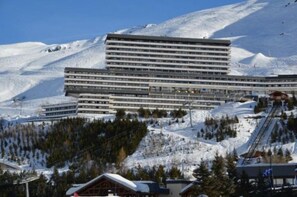A multi-story hotel with a flat roof and a ski lift in the background.