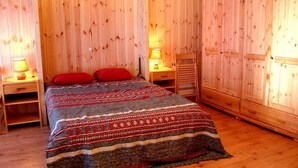 Een kamer met houten lambrisering, een bed, twee nachtkastjes en een houten garderobe.