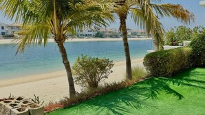 Una propiedad frente a la playa con arena, palmeras y vistas al mar.