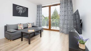 Una sala de estar moderna con un sofá gris, una mesa de centro y un televisor de pantalla plana montado en la pared.