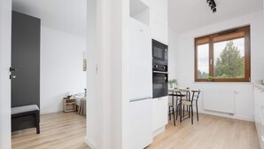 Una cocina moderna con armarios blancos, horno empotrado y comedor con mesa y sillas.