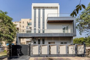 A modern two-story house with a balcony, a gated entrance, and a well-maintained garden. - Lime Tree B&B Pari Chowk (Greater Noida)