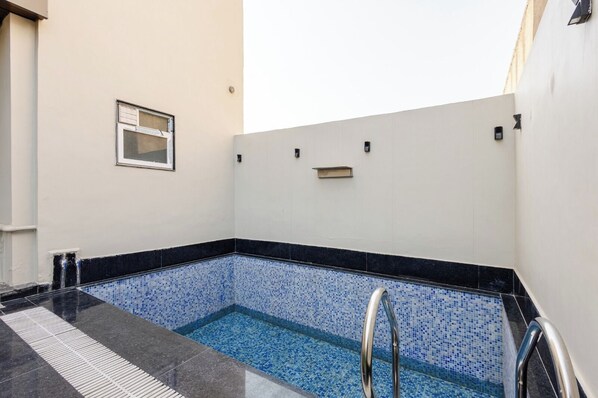 A small indoor pool with blue mosaic tiles and a metal ladder. - Lime Tree B&B Pari Chowk (Greater Noida)