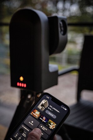 A smartphone displaying a music player interface with a speaker in the background.