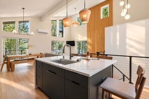 A modern kitchen with a large island, dark cabinetry, and pendant lighting.