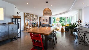 A spacious kitchen with a wooden table, modern chairs, and a large bookshelf. - VILLA NIDAZUR  VI4413 By Riviera Holiday Homes (Niza)