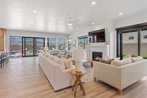 A spacious living room with a large sofa set, a fireplace, and a television. - Pecan Valley Oasis | Lux Pool & Family Retreat (Hurricane)