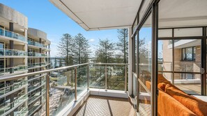 Un balcon doté de rampes en verre, donnant sur un quartier résidentiel et des arbres.