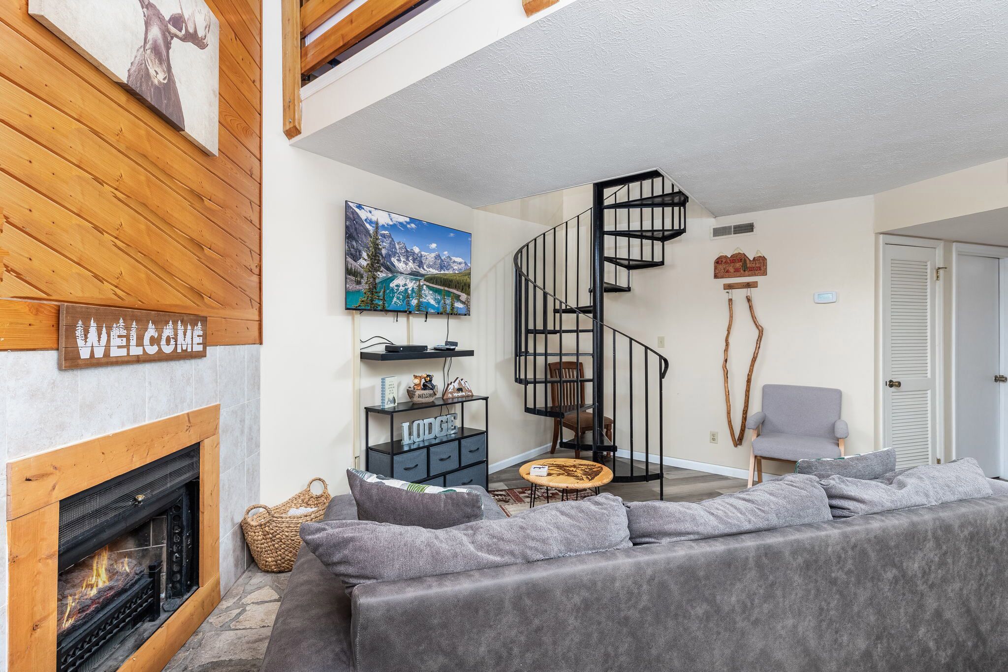 Un salon moderne avec une cheminée, un canapé, une table basse et un escalier en colimaçon.