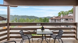 A balcony with two chairs and a table, a 'PORCH' sign, and a view of a residential area with houses and greenery.