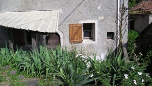 Un edificio rústico de piedra con puerta de madera, una ventana pequeña y un toldo de metal.