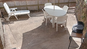 Une terrasse avec une table et des chaises, un barbecue et un parasol.