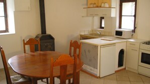 Una cocina compacta con estufa de leña, microondas y pileta.