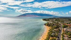 Un pueblo costero con una playa, una montaña al fondo y un cielo despejado.