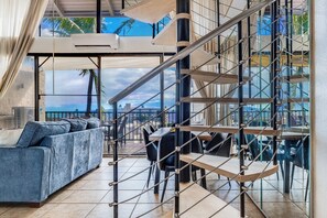 Een modern interieur met een trap, zithoek en grote ramen met uitzicht over de stad.