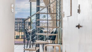 Un interior moderno con una escalera, zona de estar y grandes ventanales que ofrecen vistas de la ciudad.