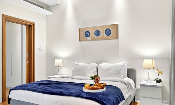 A hotel room with a bed, bedside lamps, a framed artwork, and a breakfast tray on the bed. - WYZ RENT|The perfect 1 BR City Walk in Dubai (Dubai)