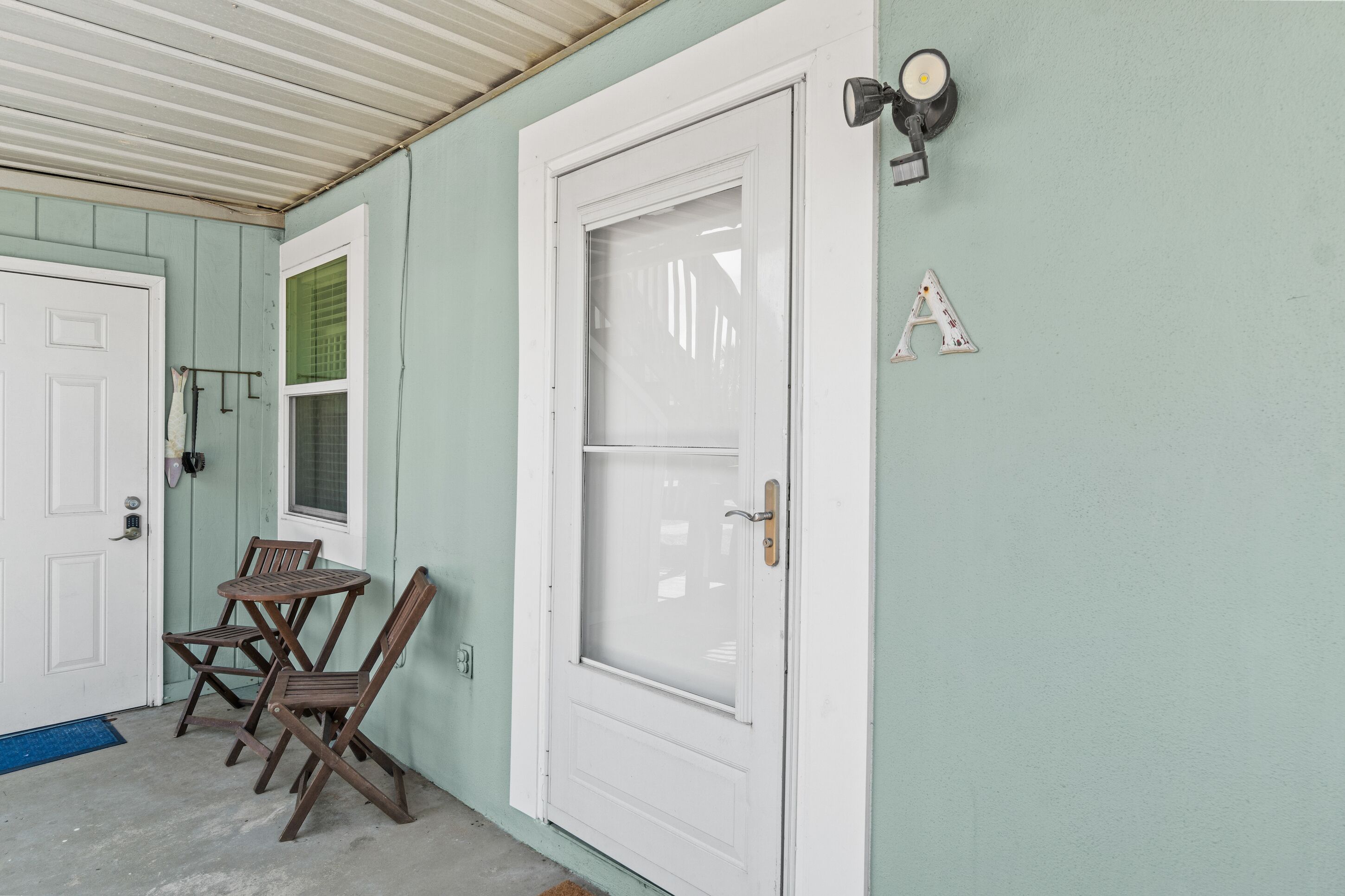 A door with a glass panel, a small table with chairs, and a wall-mounted light fixture.