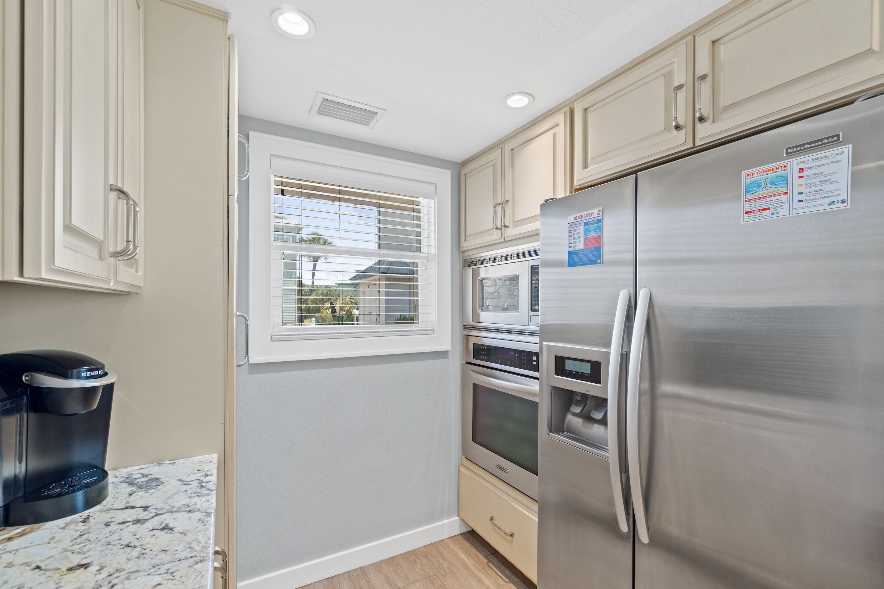 A compact kitchen with a built-in oven, microwave, and stainless steel refrigerator.
