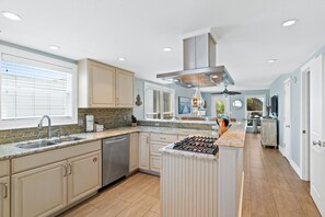 Una cocina moderna con una isla central, electrodomésticos de acero inoxidable y un amplio ventanal que proporciona luz natural.