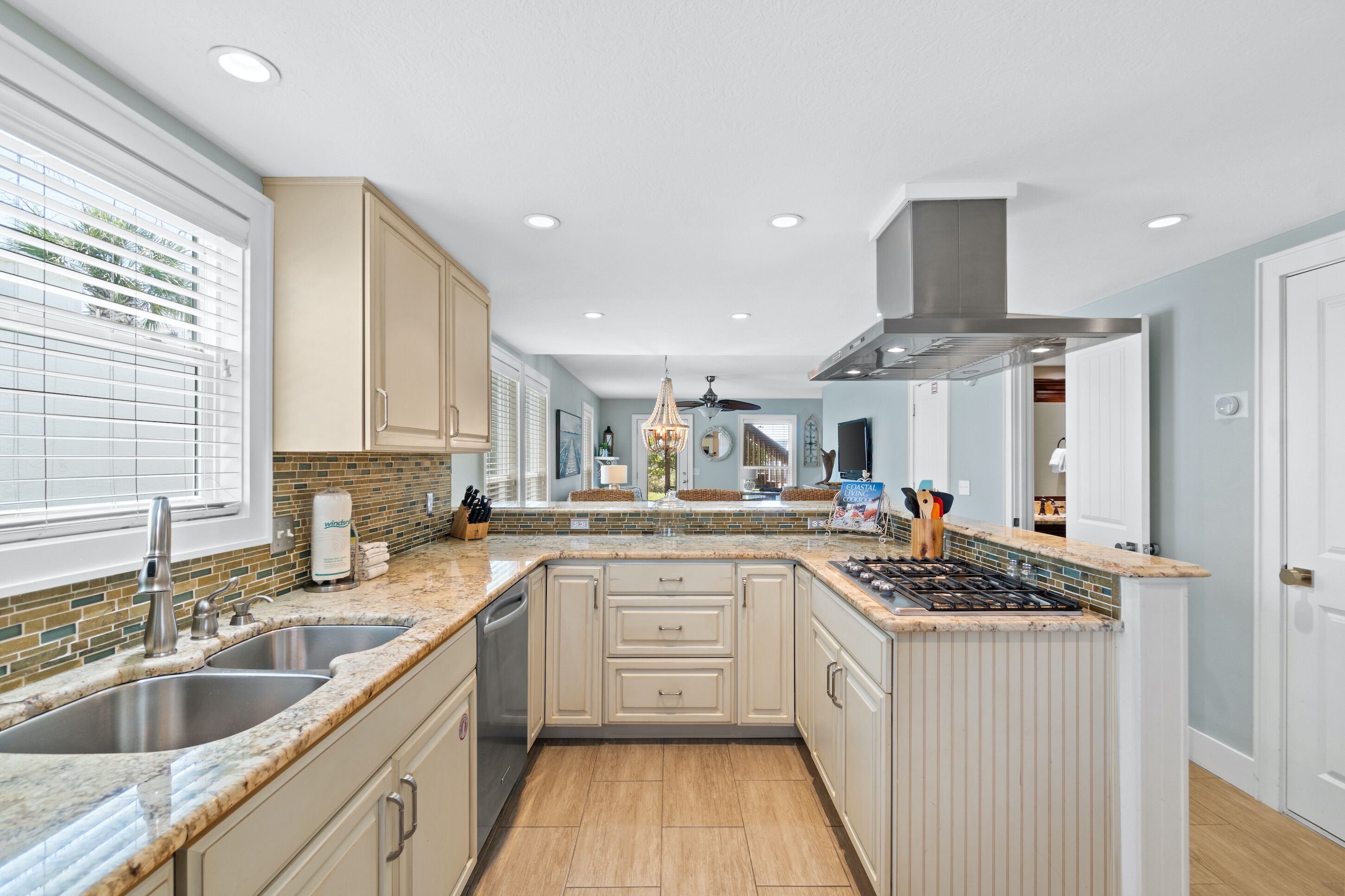 A modern kitchen with a central island, double sink, and a view into the dining area.