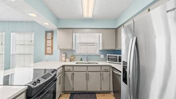 Una cocina moderna con gabinetes grises, un refrigerador de acero inoxidable, un microondas y una estufa.