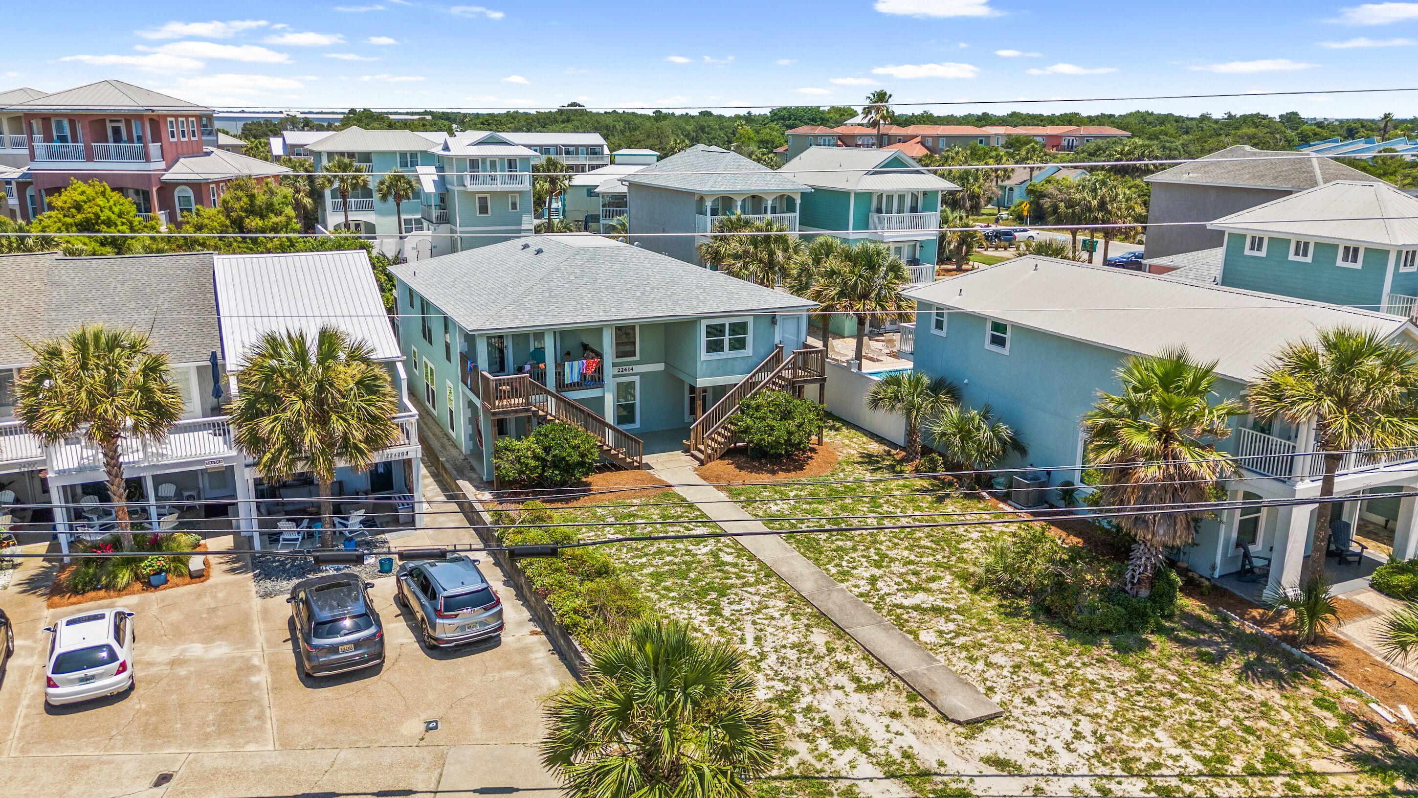A coastal residential area with multiple two-story houses, a parking lot, and a sandy beach.