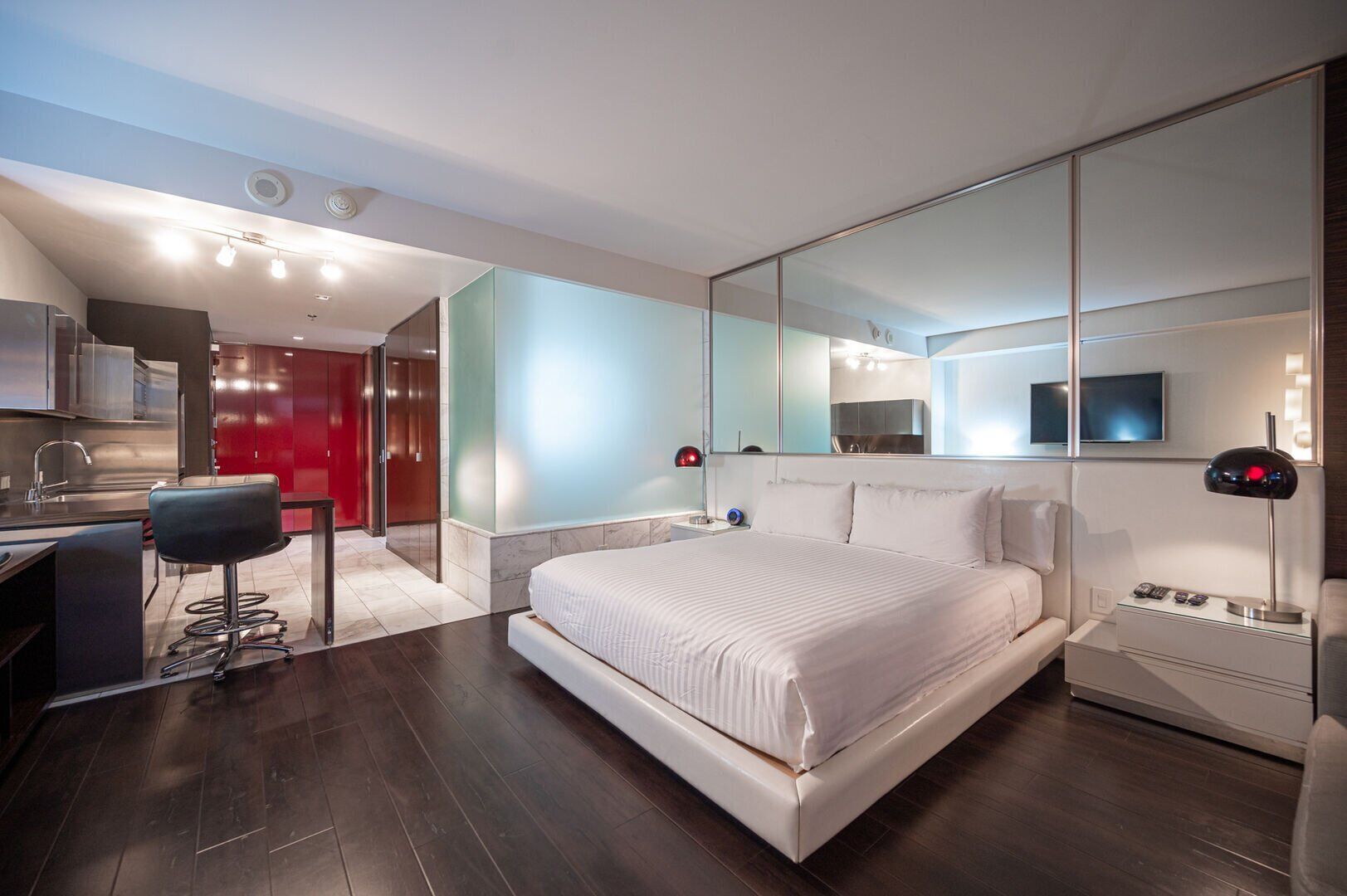 Une chambre d’hôtel moderne avec un grand lit, un bureau et un miroir.
