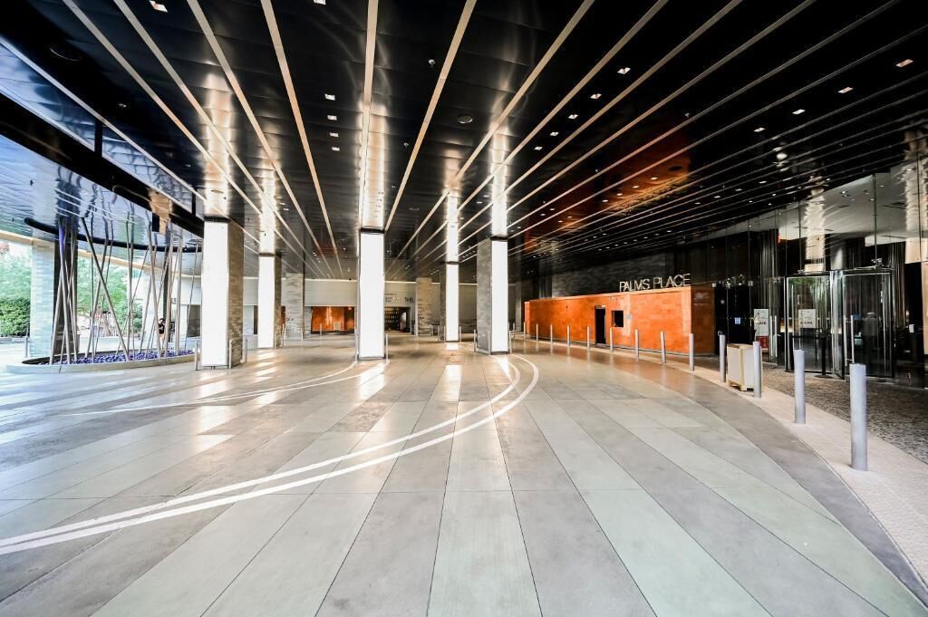 Een ruime lobby met een modern design, met een opvallende receptiebalie en een duidelijke route naar de ingang.