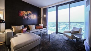 Una habitación de hotel moderna con un balcón grande, un sofá, una mesa de centro y una silla.