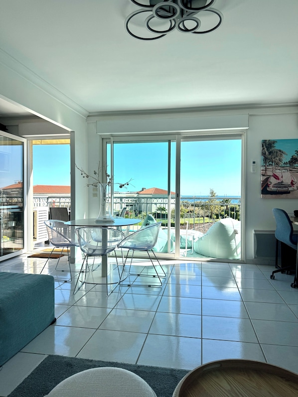 Enjoy a spacious room with a large sliding glass door leading to an outdoor area, a dining table, and a seating area with a sofa.