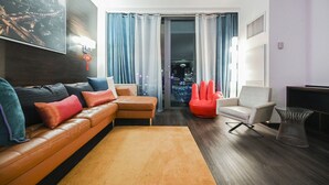 Una sala de estar moderna con un sofá de cuero, una silla roja y un sillón blanco.