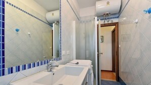 Un baño con dos lavamanos, un espejo y una zona de ducha.