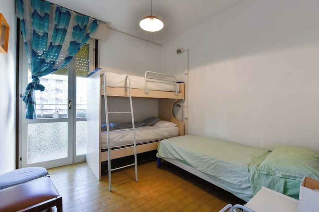 Ein Schlafsaalzimmer mit Etagenbetten, einem Schreibtisch und einem Fenster mit Vorhängen.