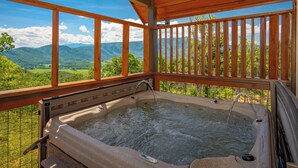 Een hottub met een houten terras en uitzicht op bergen.