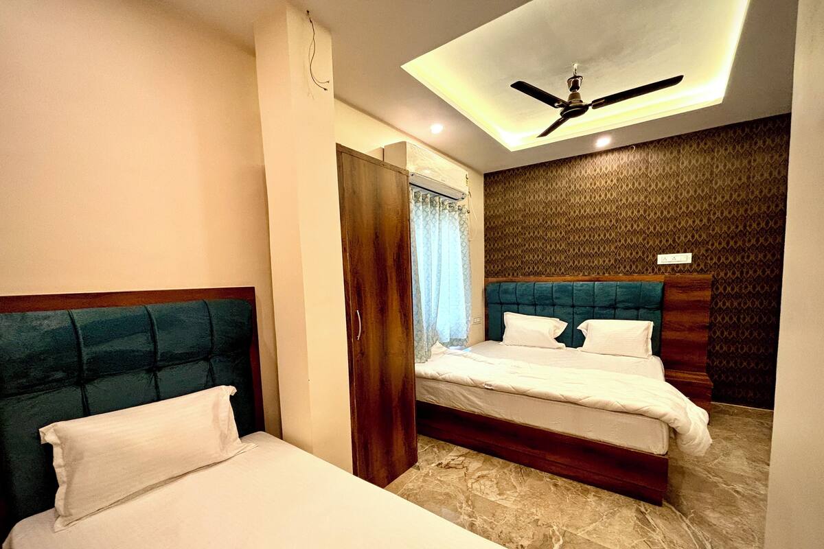 Habitación de hotel con dos camas, ventilador de techo y pared con estampado.