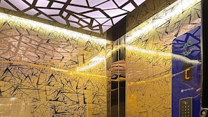 An elevator with a geometric patterned wall and a digital display with floor numbers. - VIA GANGA INN Varanasi (Varanasi)