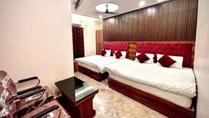 A hotel room with two beds, a desk, and a chair. - VIA GANGA INN Varanasi (Varanasi)