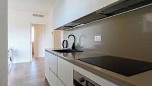 A modern kitchen with a black countertop, stainless steel appliances, and a white backsplash.