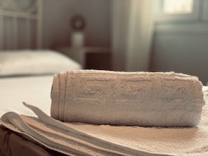 A neatly folded towel on a bed with a visible bedspread. - Tinos 4 Person House in Heart of Tinos Island (Tinos)