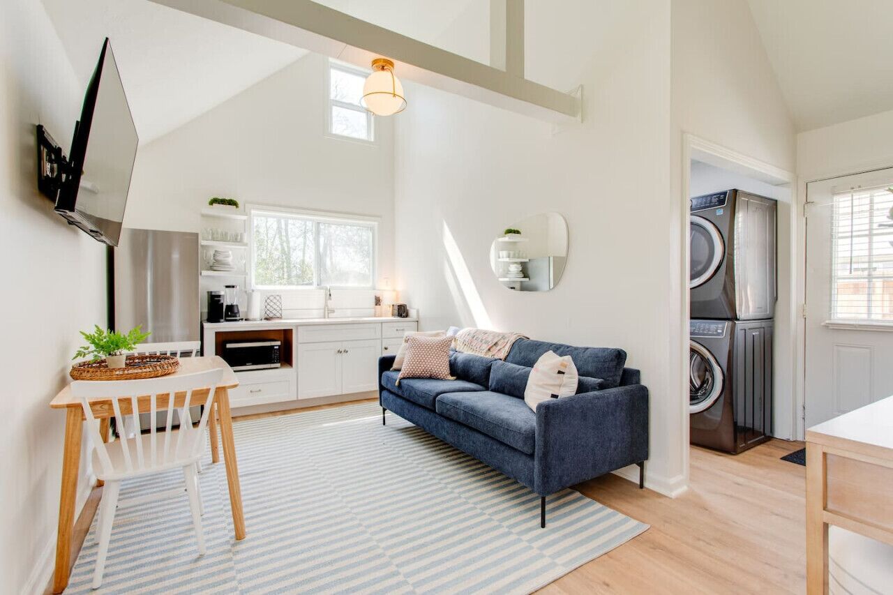 A compact living space with a kitchenette, a sofa, a dining area, and a laundry room.
