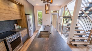 Una cucina moderna con isola centrale, elettrodomestici in acciaio inossidabile e una scala in legno.