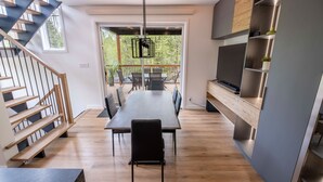 Una cucina moderna con zona pranzo, una scala in legno e vista all'esterno.