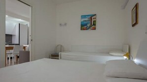 A bedroom with a bed, a desk, and a chair. There is a painting on the wall.
