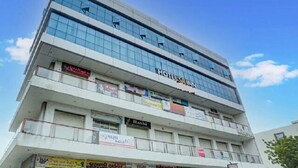 A multi-story hotel with a modern glass facade. - Hotel SR Inn (Anand)