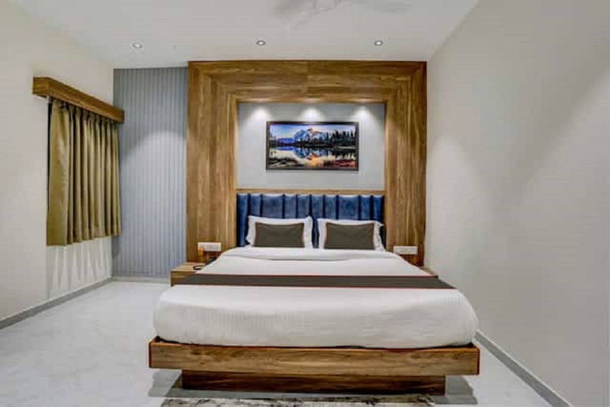 A modern bedroom with a wooden headboard, a large bed, and a painting above it.