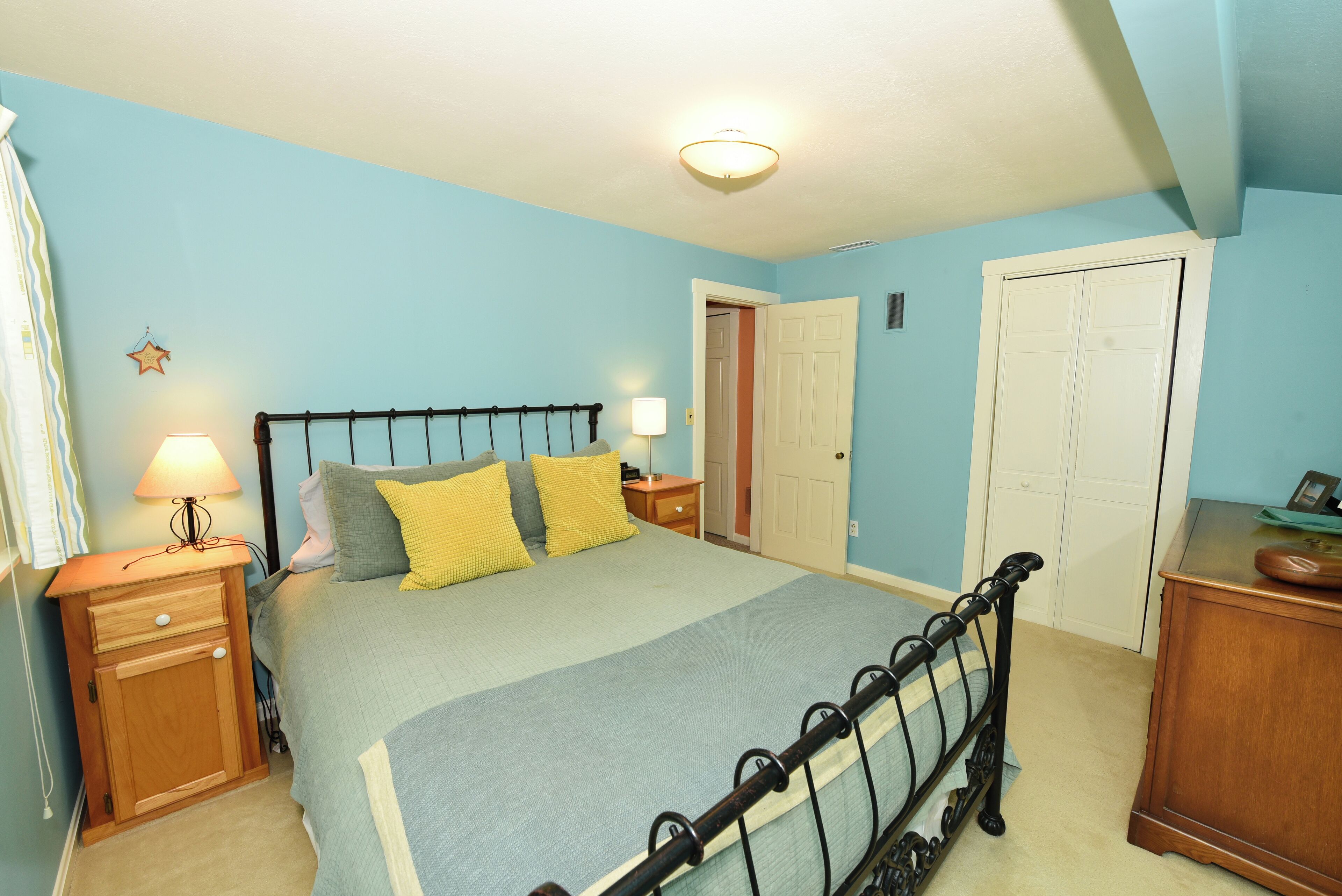 A bedroom with a bed, nightstands, a dresser, and a door.