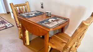 Una mesa de madera para comer con dos sillas a juego, un mantel individual estampado y un pequeño adorno sobre la mesa.