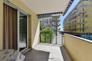 Un balcone con una porta in vetro, un piccolo tappeto e una ringhiera in metallo.